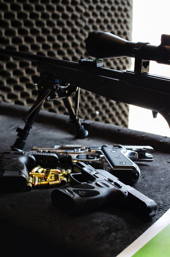 Services Close-up of various firearms and ammunition on a shooting range table in São Paulo, Brazil.