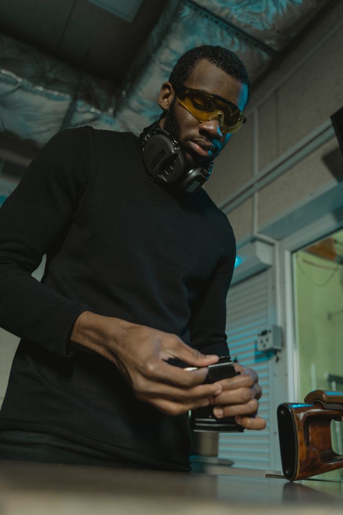 Crafting Captivating Headlines: Your awesome post title goes here Man wearing protective gear assembling a gun magazine indoors.