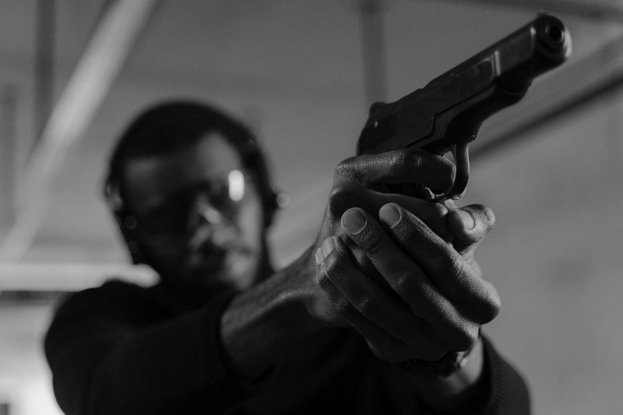 The Art of Drawing Readers In: Your attractive post title goes here Black and white photo of a man aiming a handgun at an indoor shooting range.