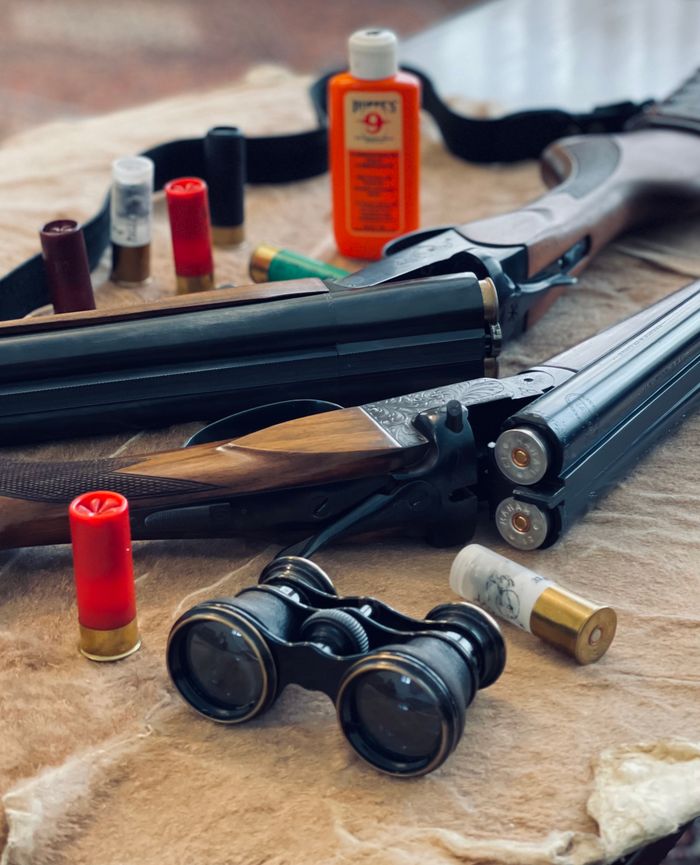 Mastering the First Impression: Your intriguing post title goes here Shotgun with ammunition and binoculars on fur. Ideal for hunting themes.